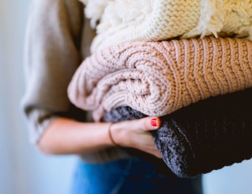 Konmari method for your money — a woman holds a stack of folded sweaters