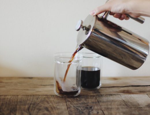 Hand holding French press and pouring coffee ; What's the real cost of convenience?